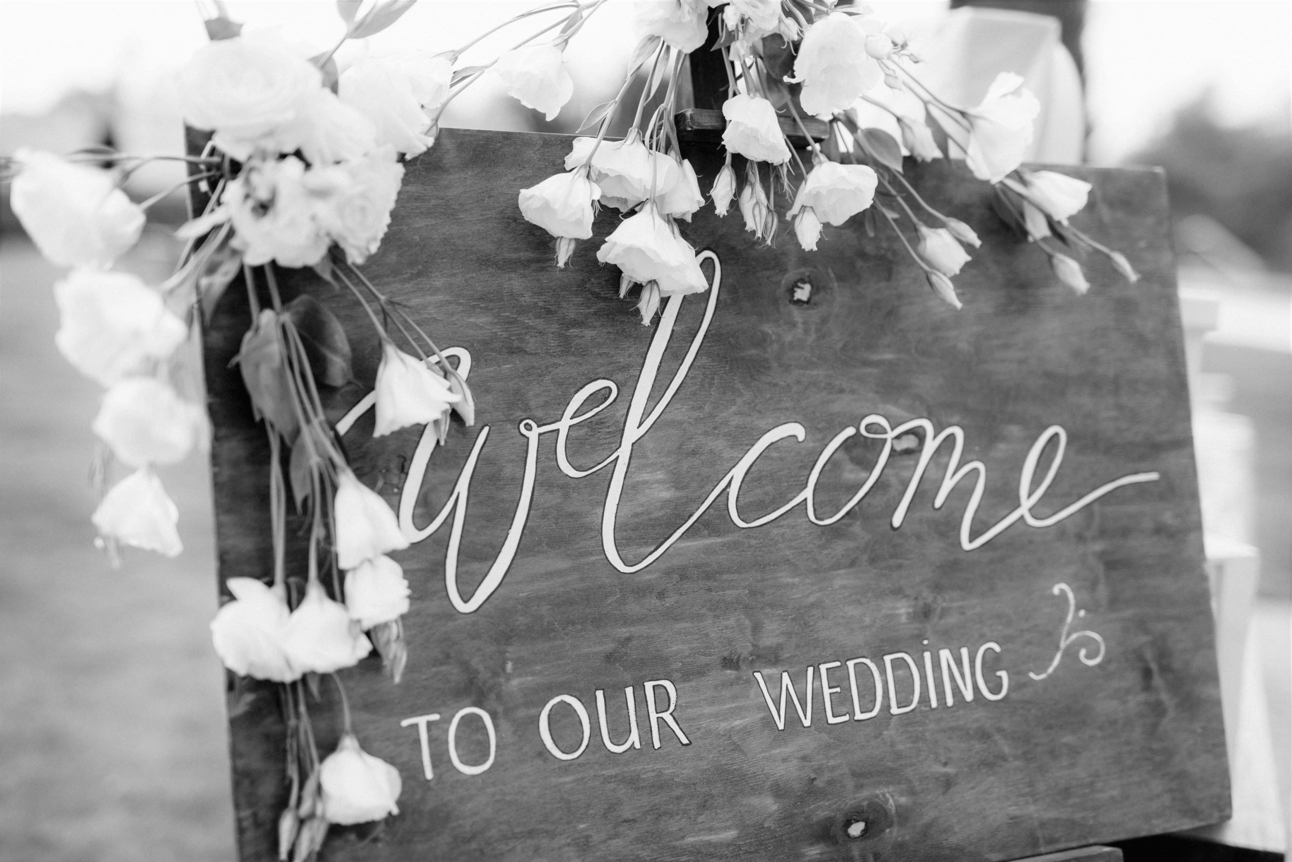 black and white image of wooden welcome sign with white flowers
